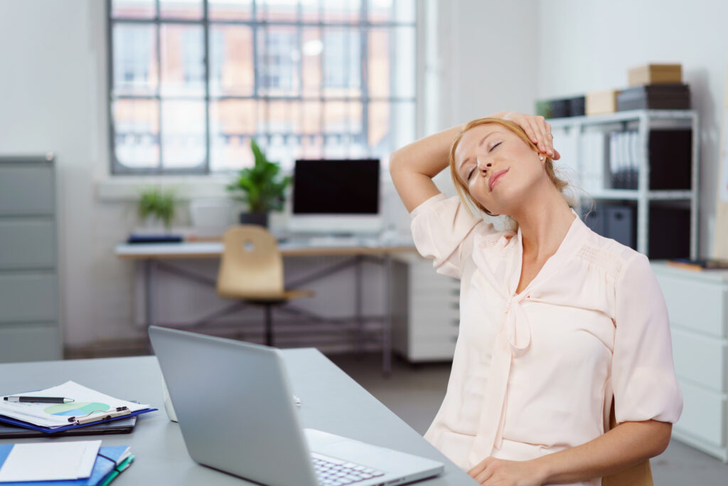 Junge Frau macht Übungen zur Nackenentspannung im Büro.